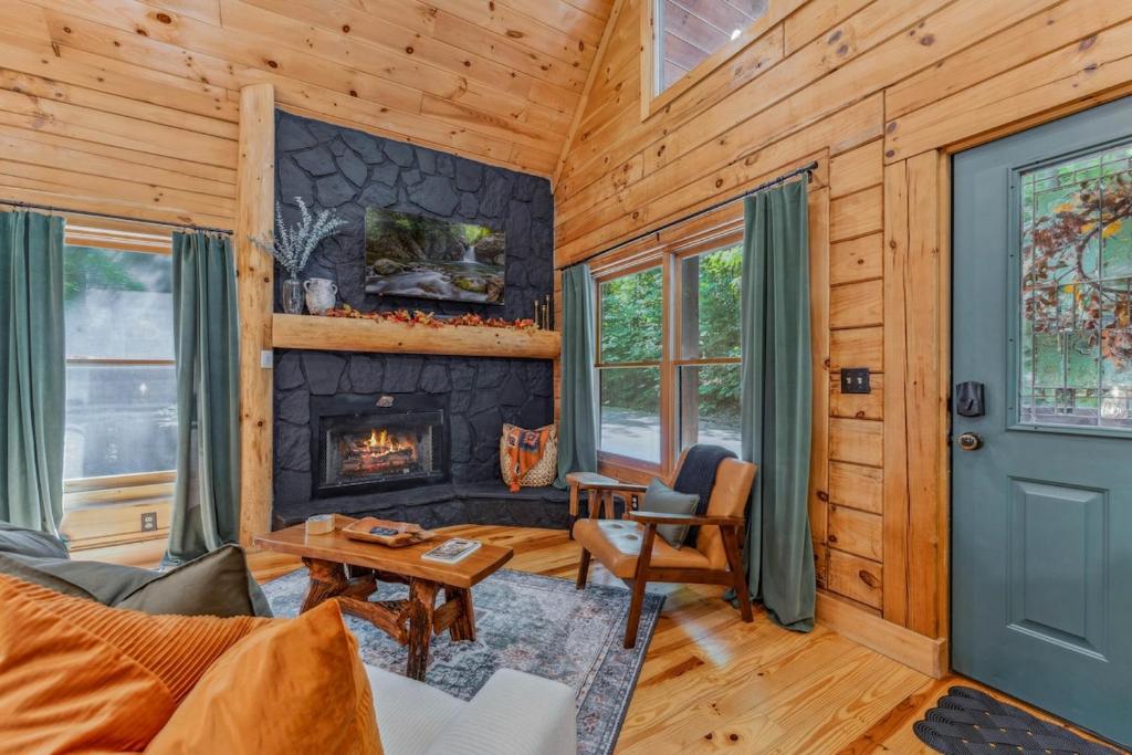 The living room built around a black stone fireplace and log mantel · © Little Pine Lodge