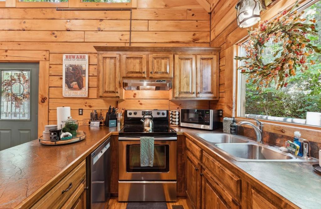 The full kitchen with a stainless range under a forest-facing window · © Little Pine Lodge