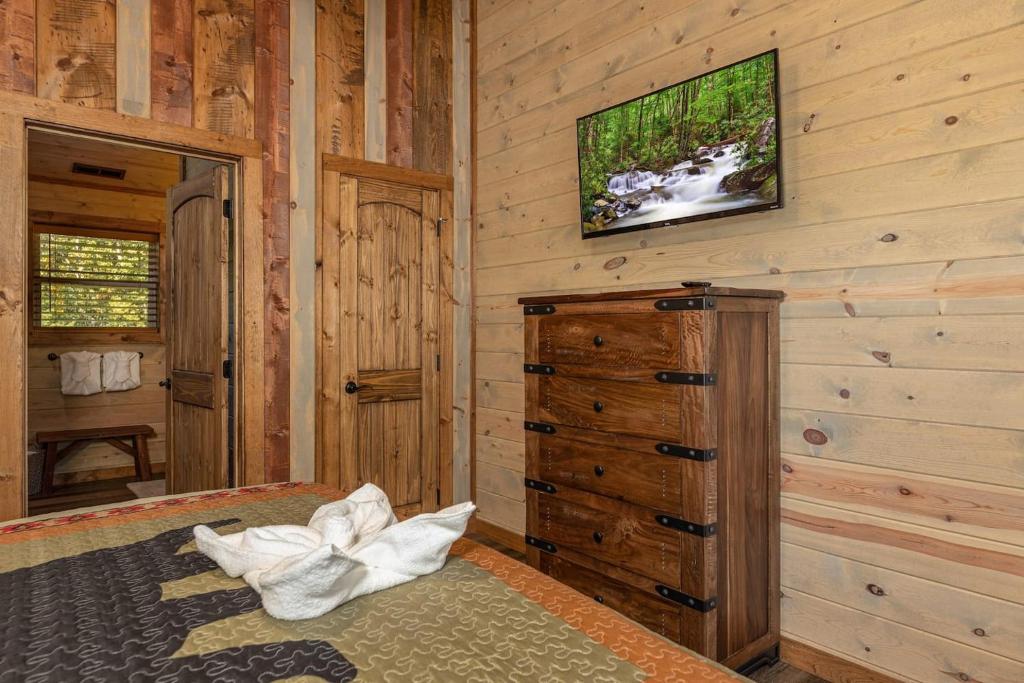 A second bedroom with a dresser and wall-mounted TV · © Lux Cabin Mtn Views