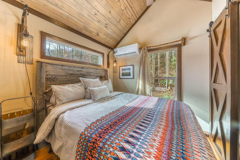The bedroom with a barn door and windows onto the trees · © Mill Creek Tiny House