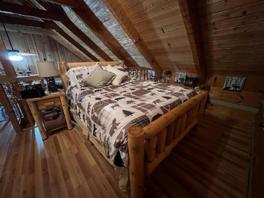 The loft bedroom under the timber eaves, bear-print quilt on the log bed · © MoonPie Hideaway
