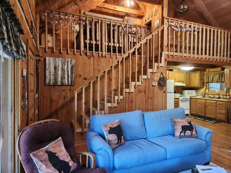 Open living and kitchen with the loft stair climbing the log wall · © MoonPie Hideaway