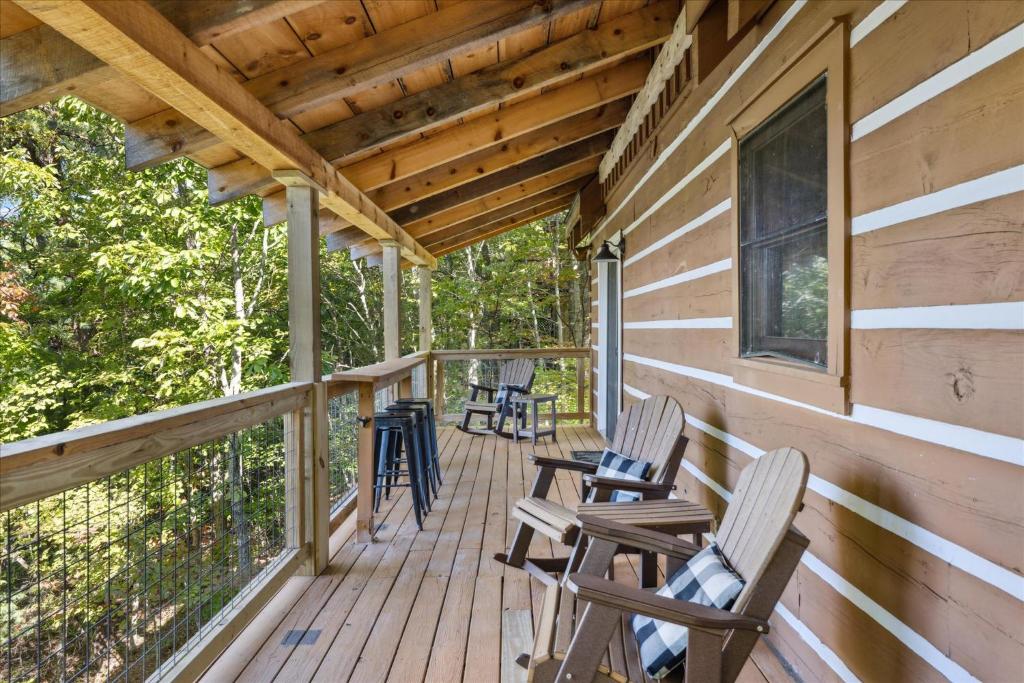 A covered deck with rockers and bar stools facing the woods · © Mountain Haven Cabin