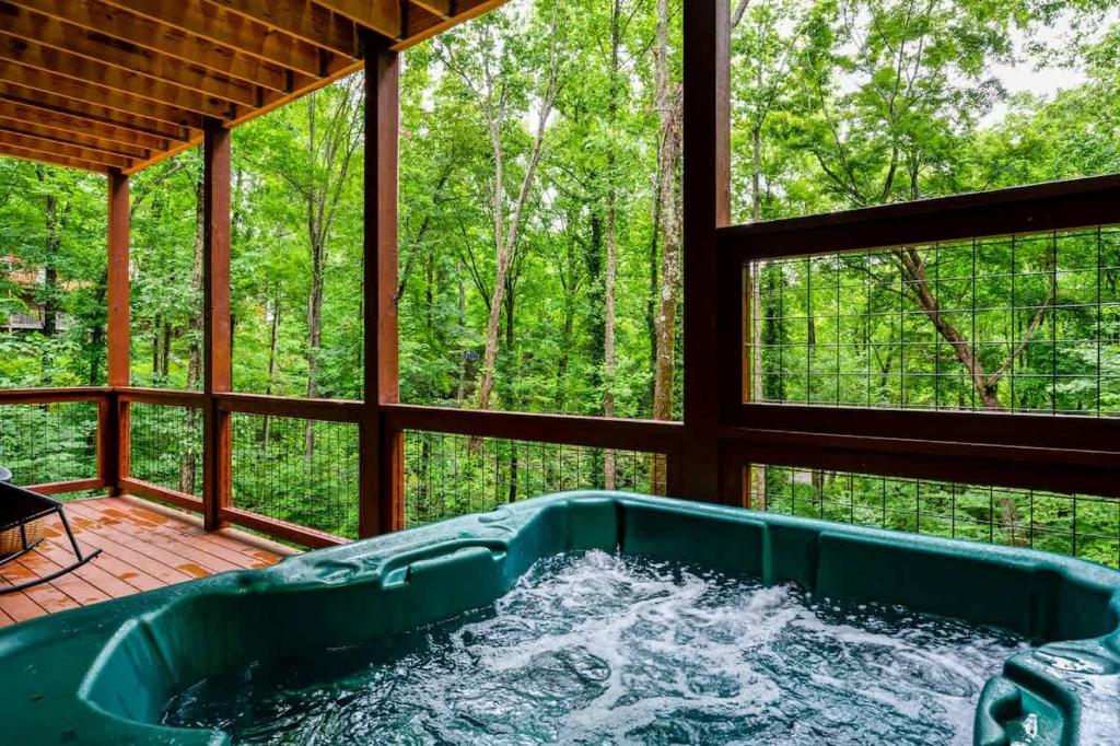 The private hot tub on the covered deck, facing the hardwoods · © Theo's Treehouse