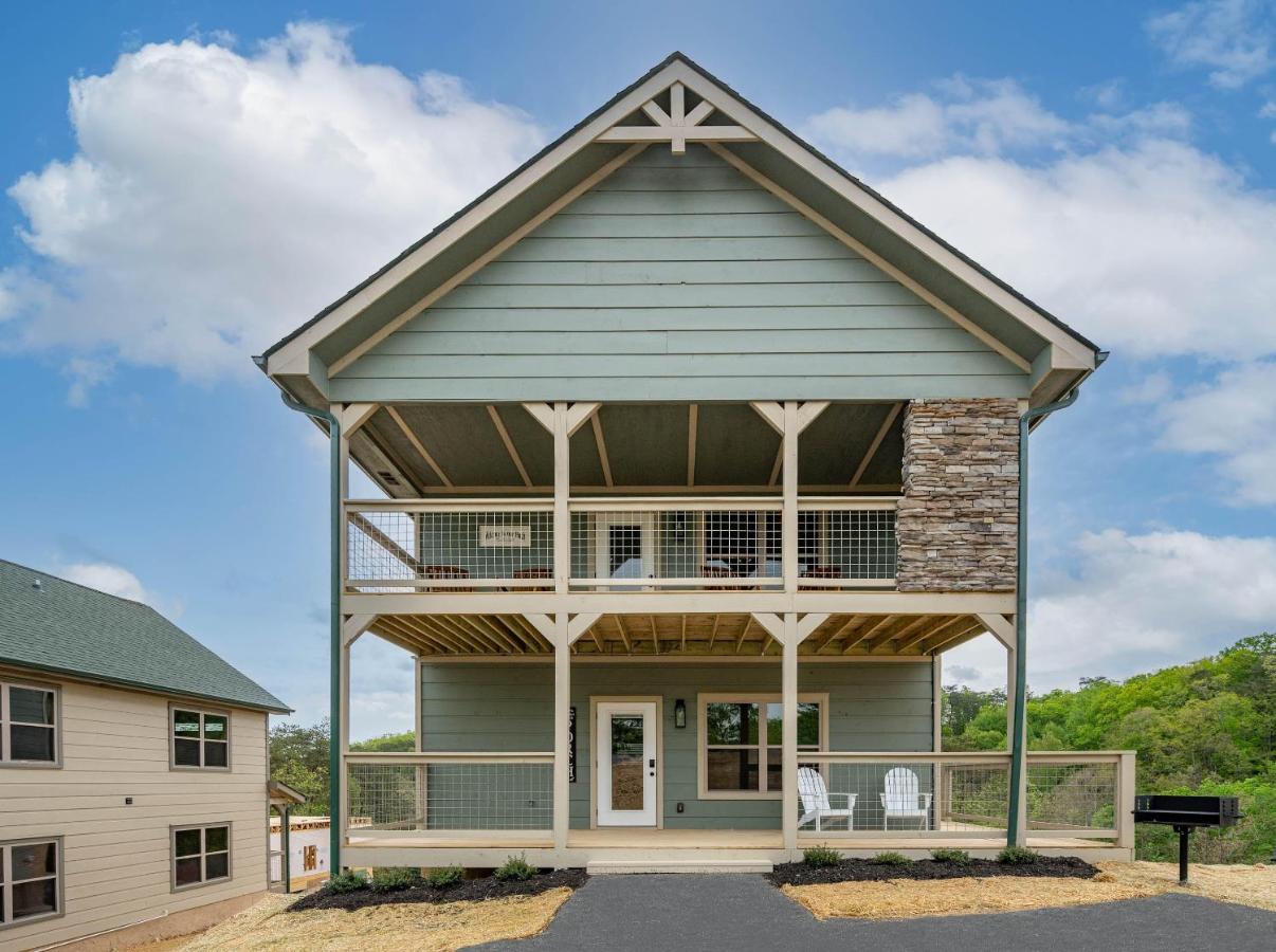 The green cabin and its two-level covered porches from the drive · © Osprey Nest Cottage