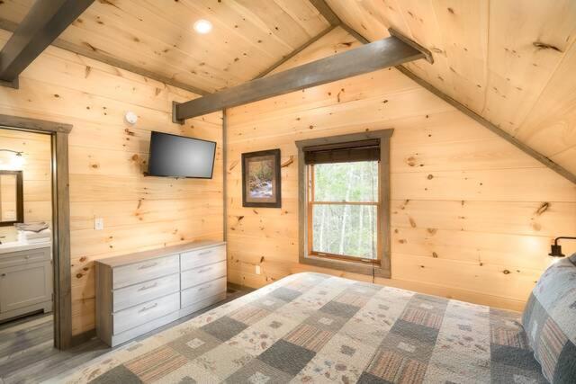 A king bedroom under a vaulted pine ceiling · © Peaceful Escape