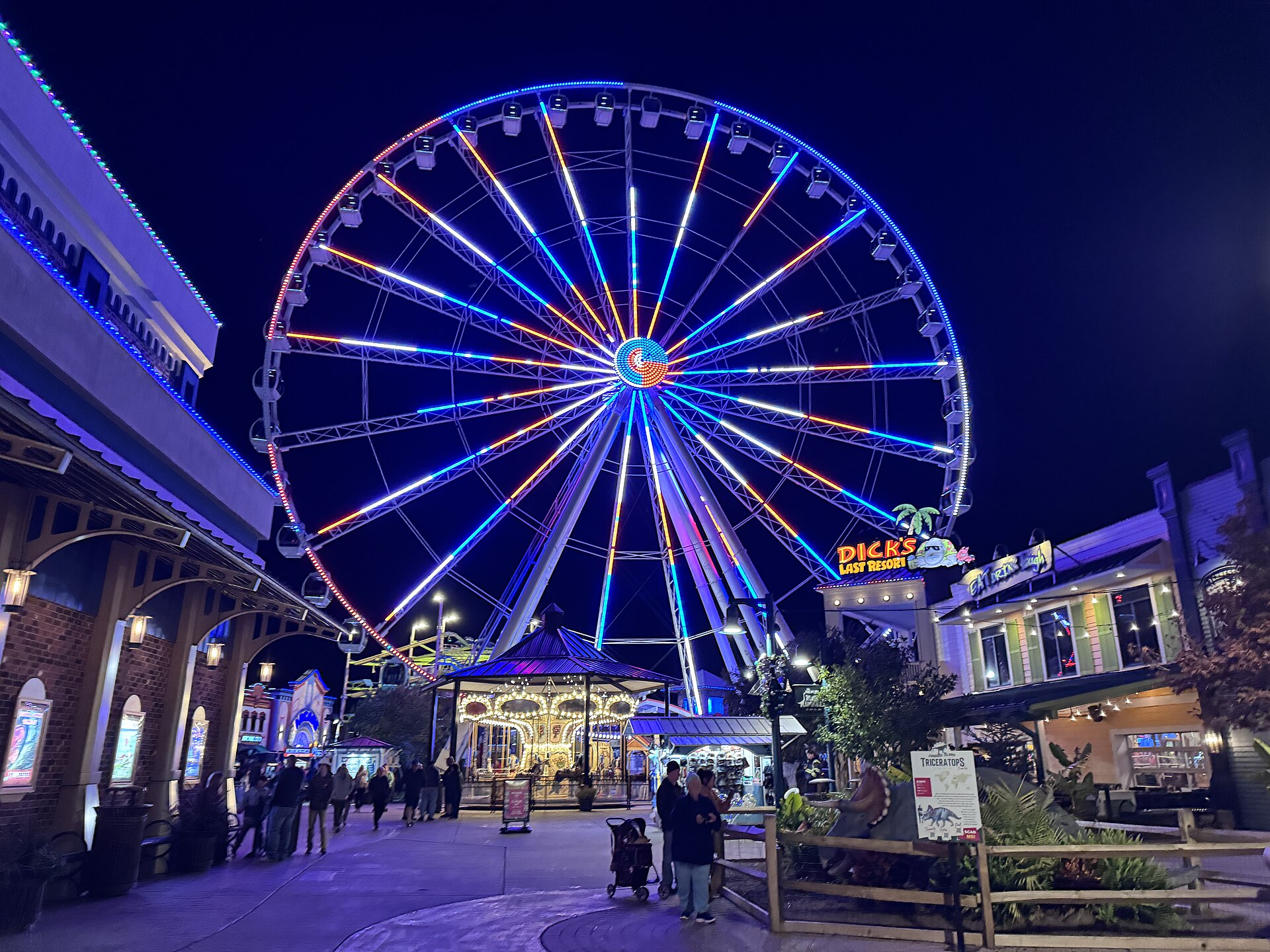 The Wheel lit up at night over The Island's walkway and carousel