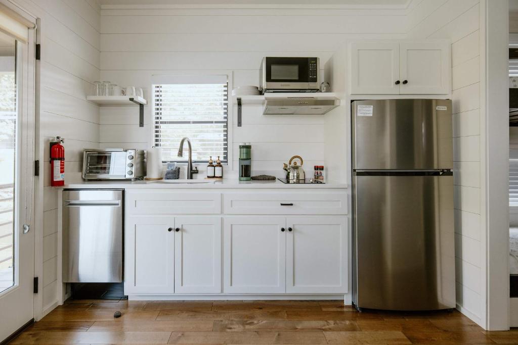 The white shaker kitchen with dishwasher and stainless fridge · © Racoon Cabin
