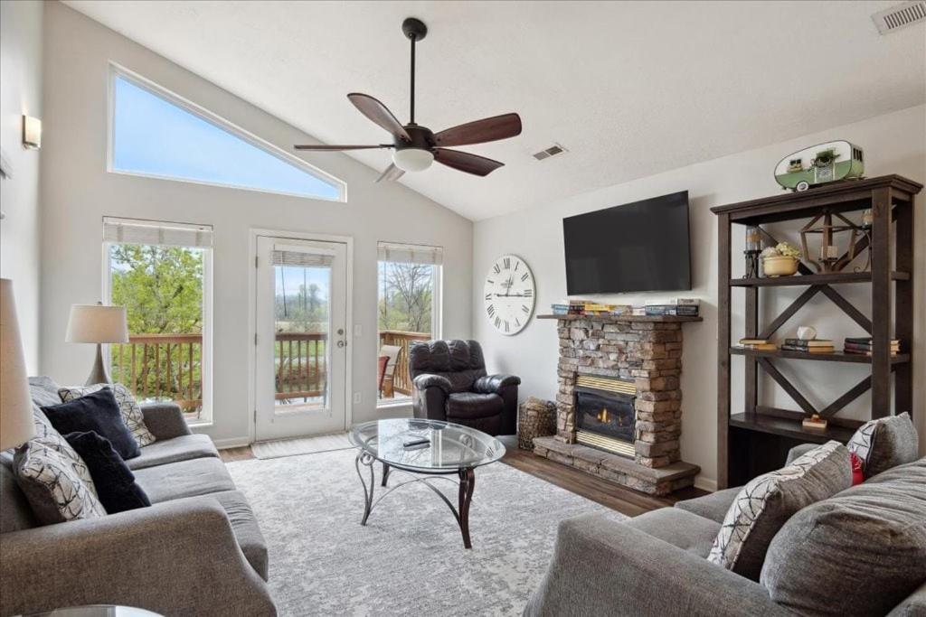 The great room under a vaulted ceiling, around a stone gas fireplace · © River Oar'asis