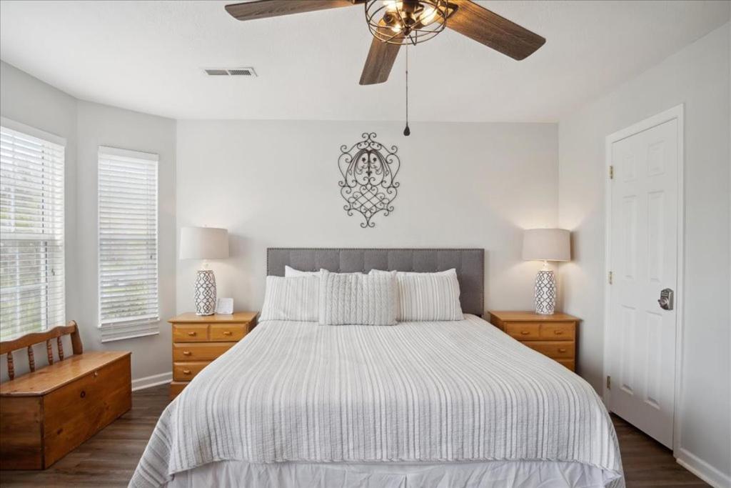 A king bedroom in white linens with a bright corner window · © River Oar'asis
