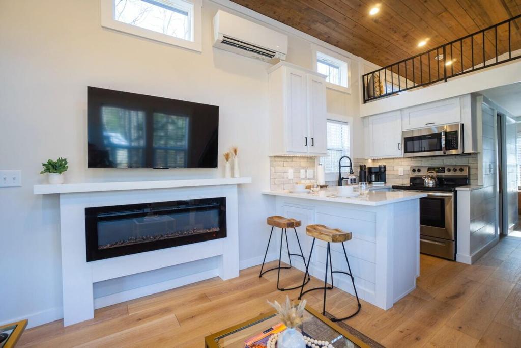 The electric fireplace beneath the TV, kitchen bar beyond · © Sage Cabin