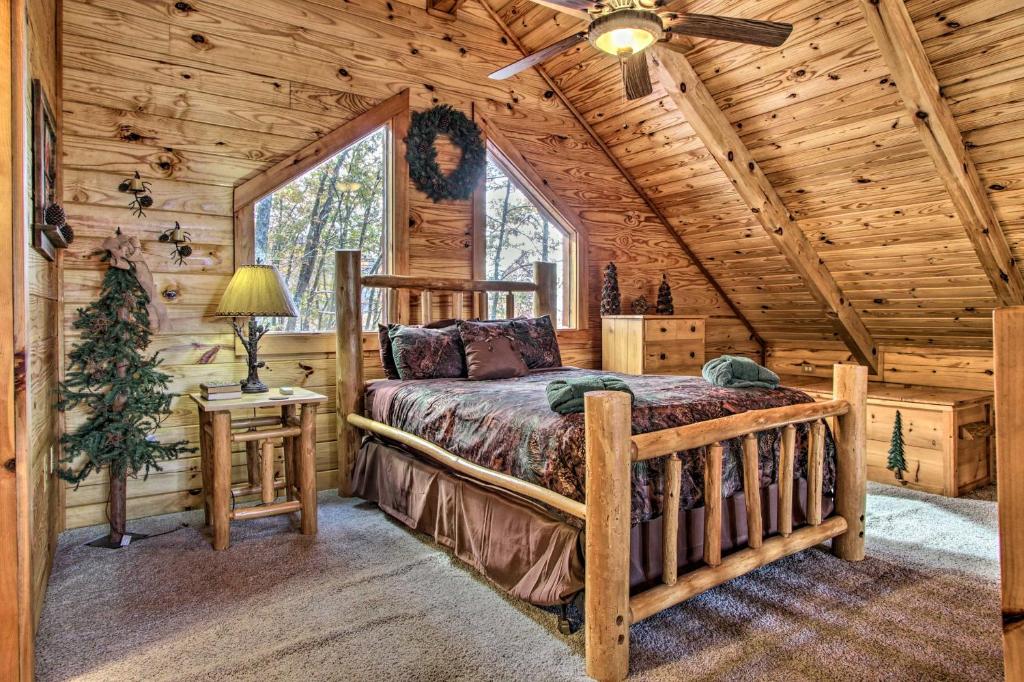 A log-frame queen bed under the pitched pine ceiling · © The Wraparound Deck Cabin