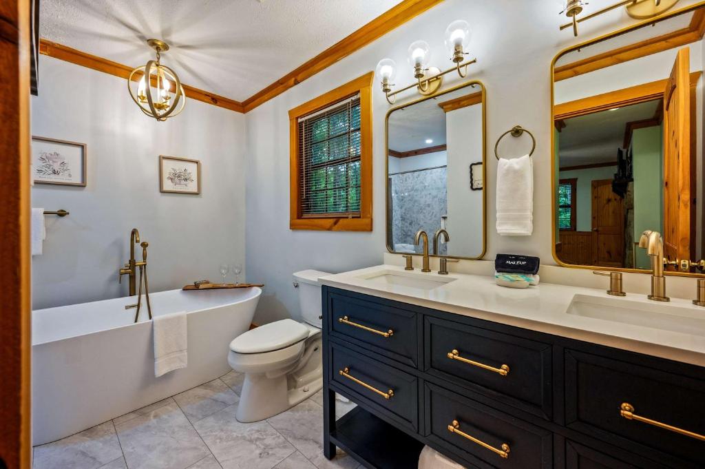 The freestanding tub and double vanity in brass and navy · © Serene Escape