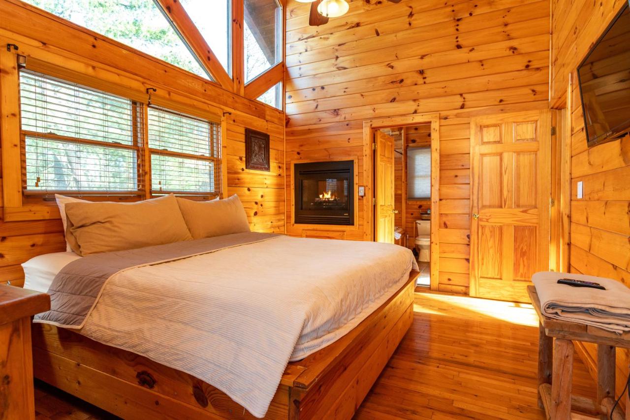 A king bedroom with its own fireplace and treetop windows · © Sereni-Tree Log Cabin