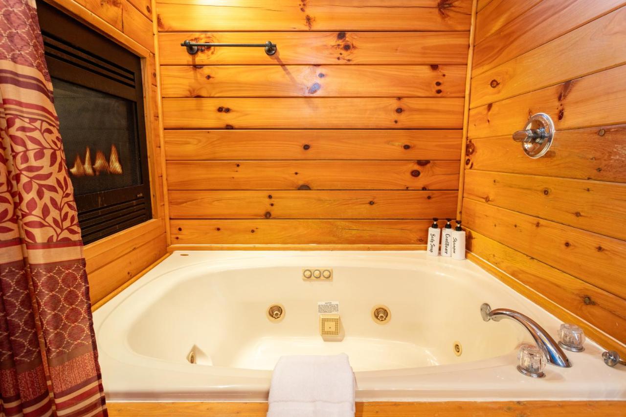 The jetted spa tub set beside a fireplace in the bath · © Sereni-Tree Log Cabin