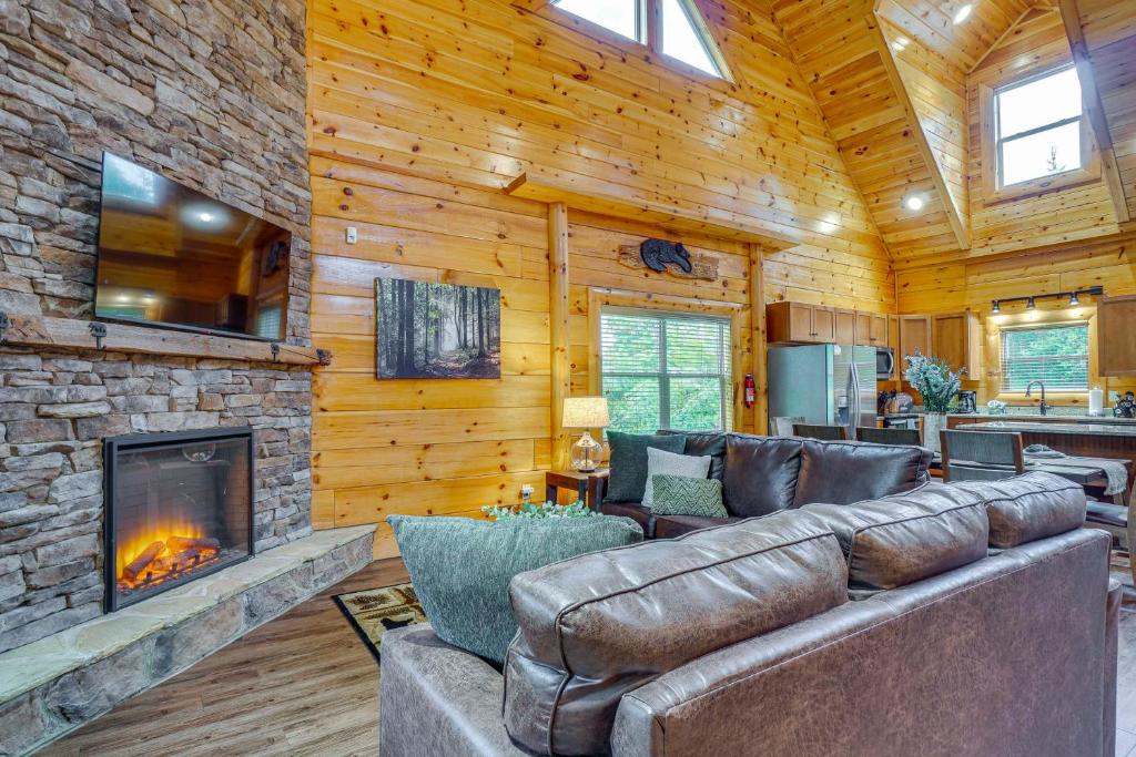 Leather sofas facing the stone-walled fireplace under a vaulted ceiling · © Shady Pines