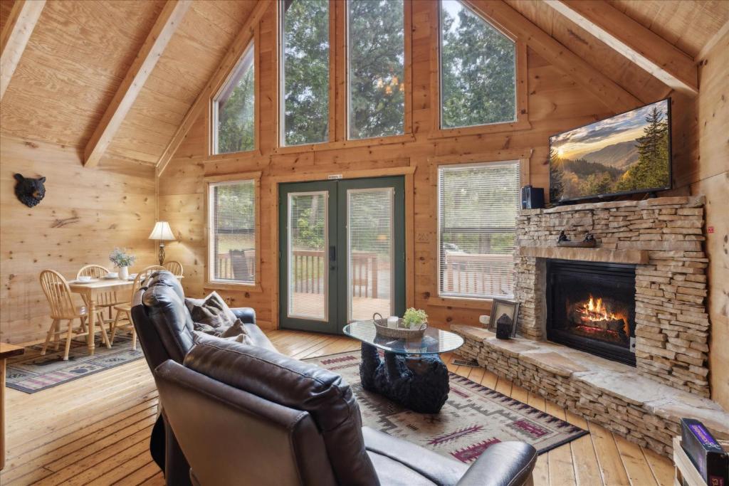 The living room under the glass gable, with a stone gas fireplace · © Smoky Oaks