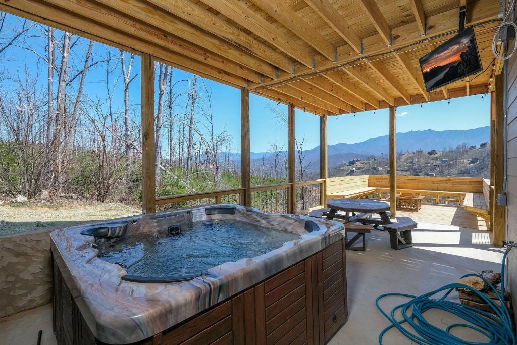 The hot tub on the covered patio, mountains beyond · © Splash 'N Heavenly Views