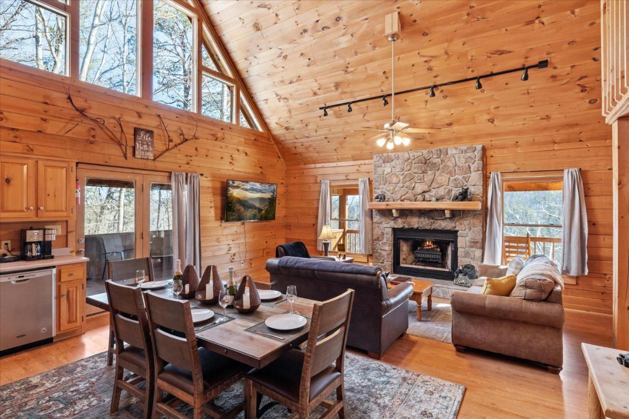 The vaulted living room, stone fireplace and dining table under the timber ceiling · © SunnySierra Cabin