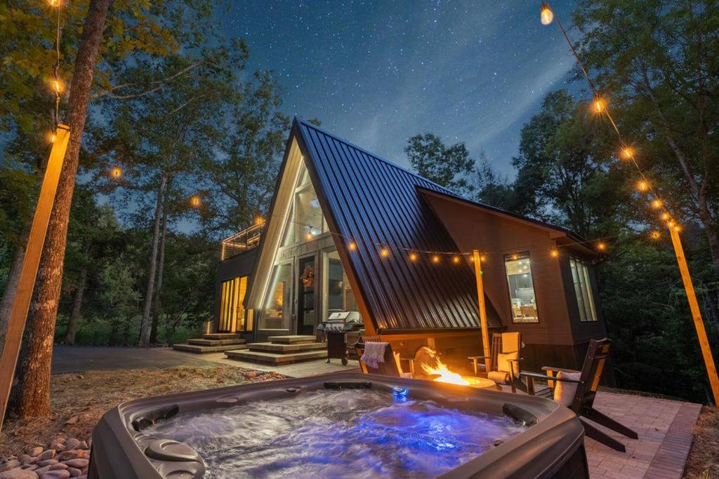 The hot tub and fire pit under string lights and stars · © The Bold Covemont A-Frame