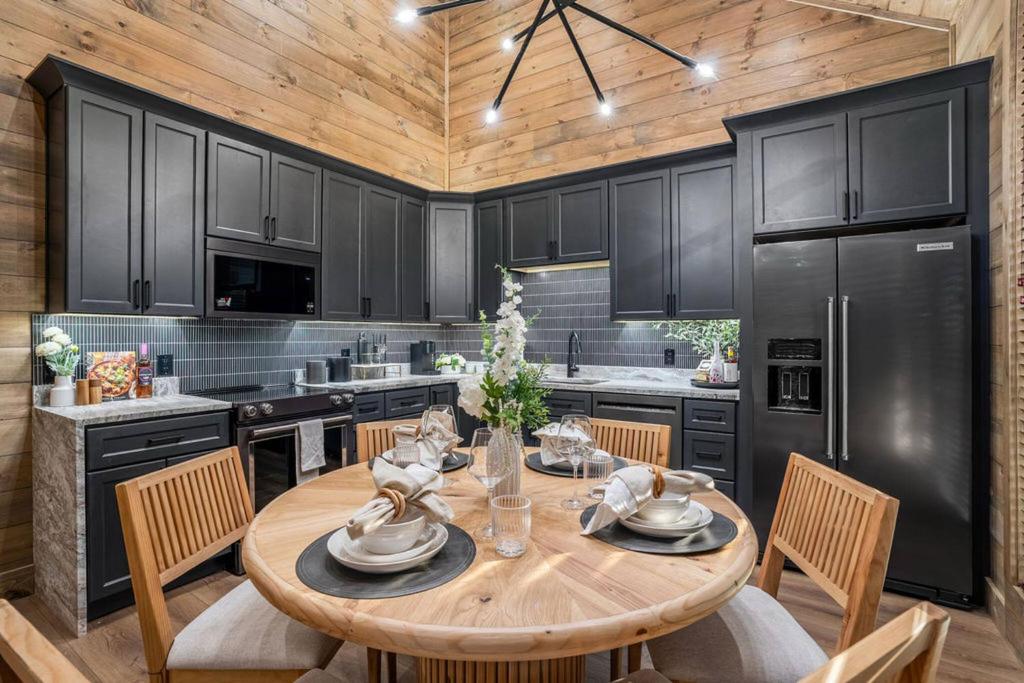 The dark-cabinet kitchen and round dining table · © The Bold Covemont A-Frame