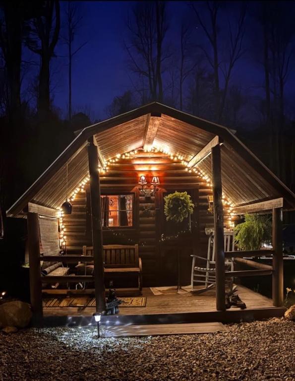 The log cabin and its covered porch lit up at night · © The Dapper Duck Log Cabin