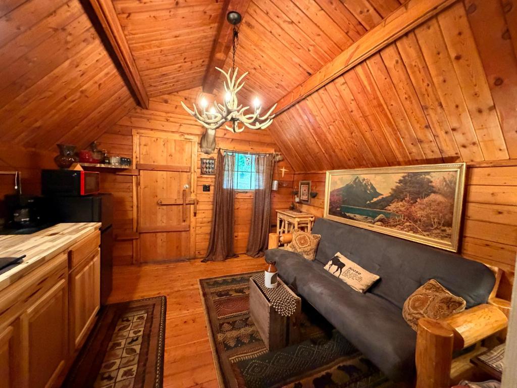 The living room under a vaulted pine ceiling and antler chandelier · © The Dapper Duck Log Cabin