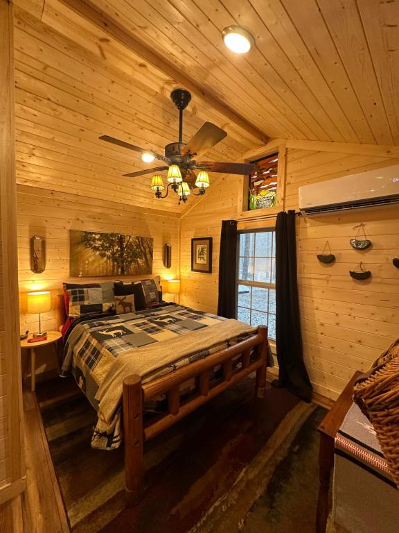 The bedroom with its log-frame bed and plaid quilt · © The Dapper Duck Log Cabin