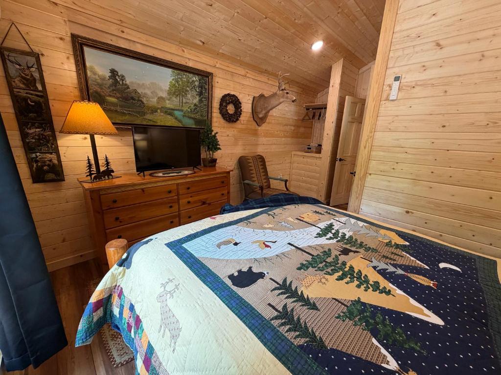 The bedroom under a Smoky Mountains quilt, with a TV on the dresser · © The Drake Cabin in The Forest