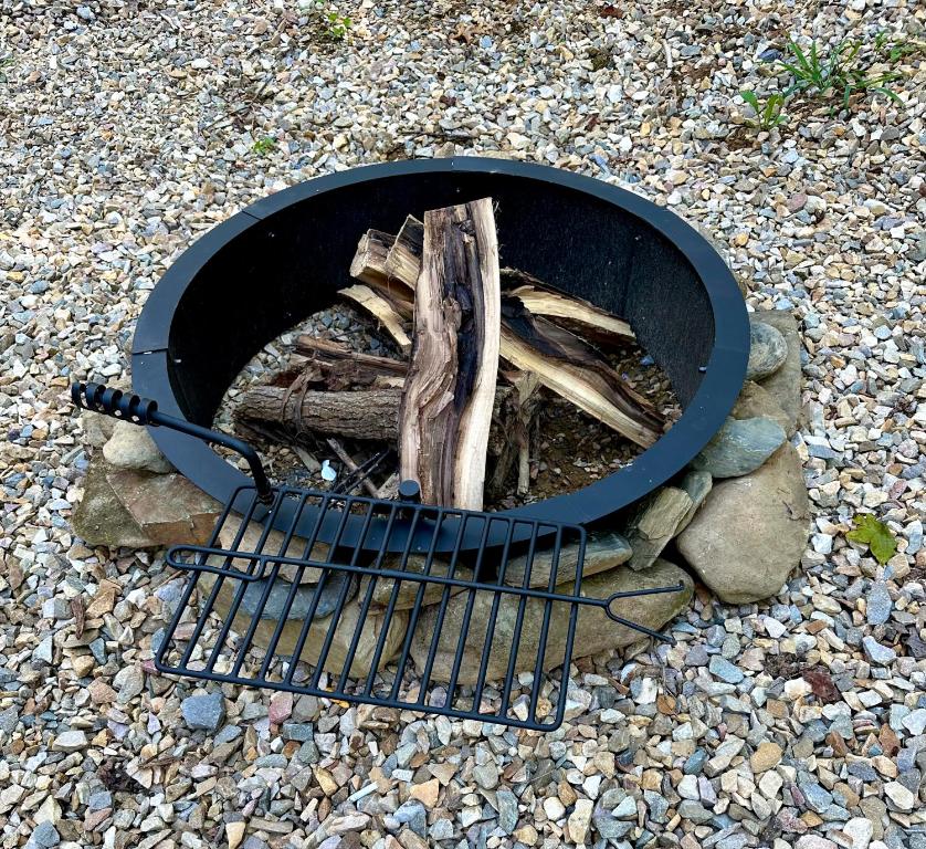 The stone fire pit and grill grate set in the gravel yard · © The Drake Cabin in The Forest