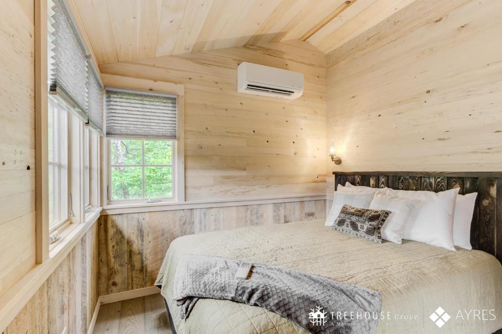 A bedroom lined in pale timber boards · © The Moosewood at Treehouse Grove