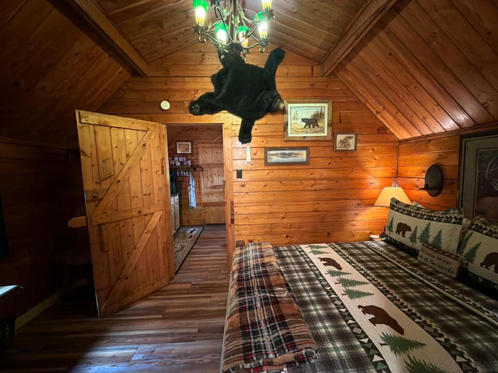 The bedroom in bear-print bedding beneath a pine ceiling · © The Raven