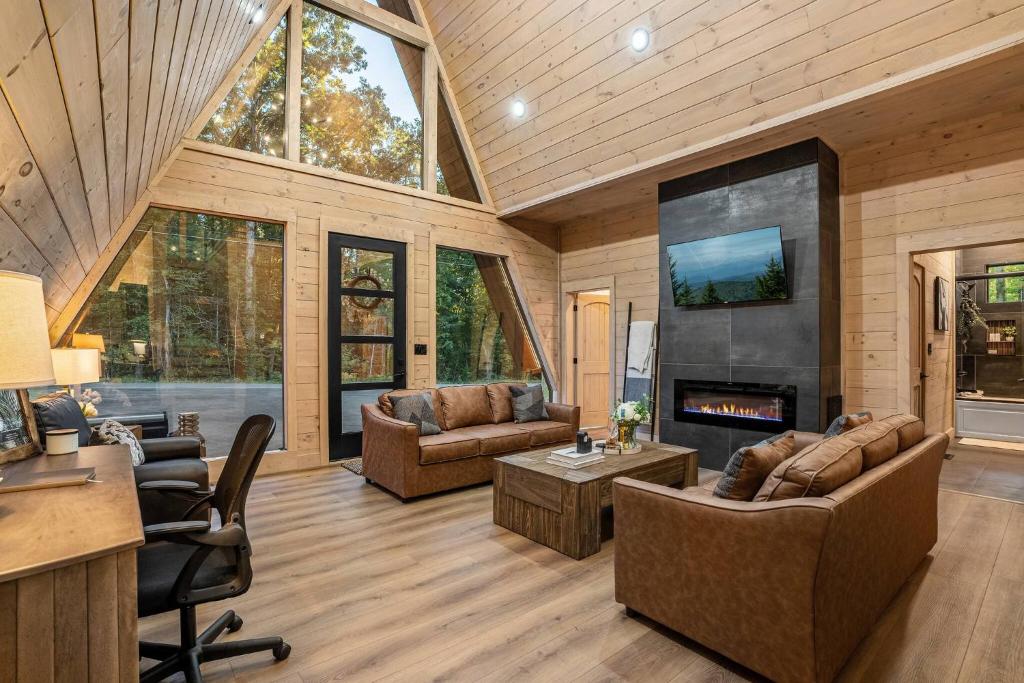 The living room under the glass gable, with the tiled fireplace · © The Sleek Covemont A-Frame