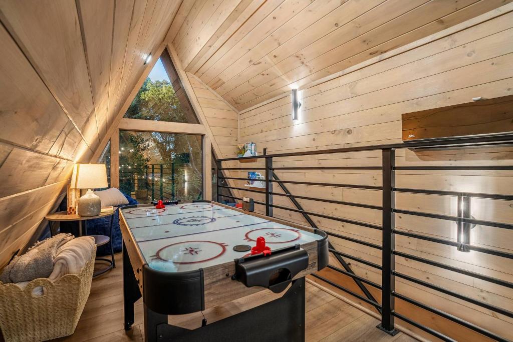 Air hockey in the loft, looking out through the gable window · © The Sleek Covemont A-Frame