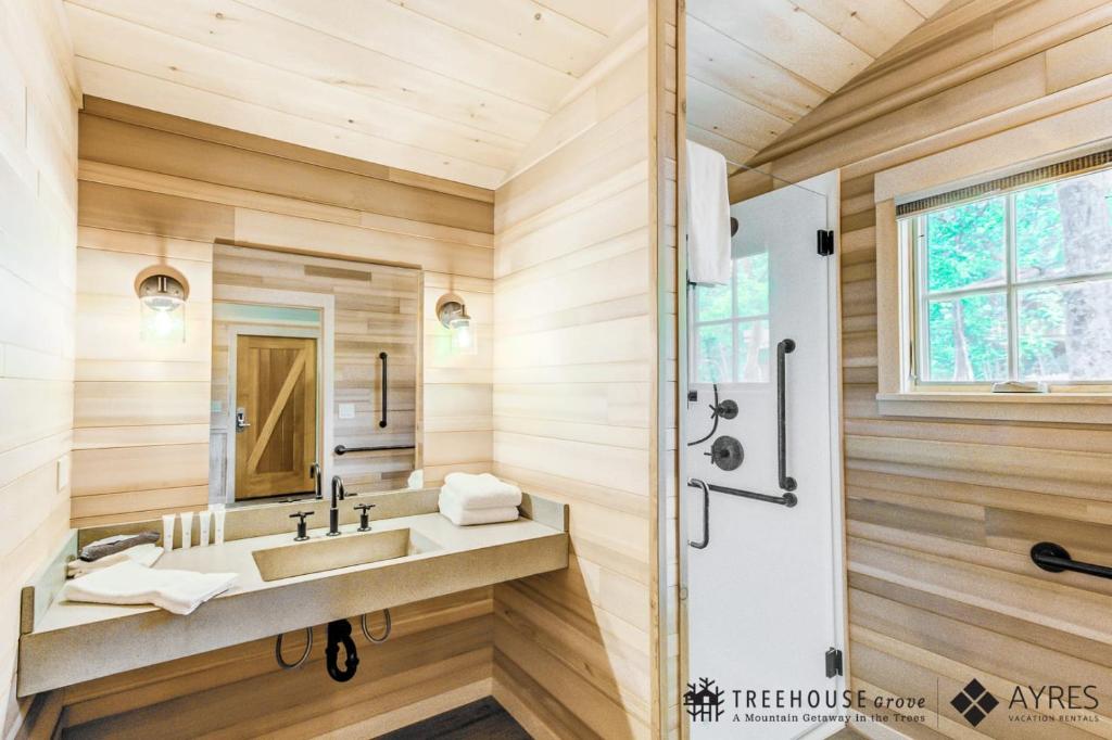 A pale-wood bathroom with a walk-in shower · © The Spruce at Treehouse Grove