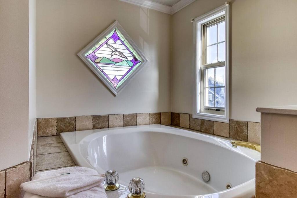 The jetted tub under a stained-glass mountain window · © Top of World
