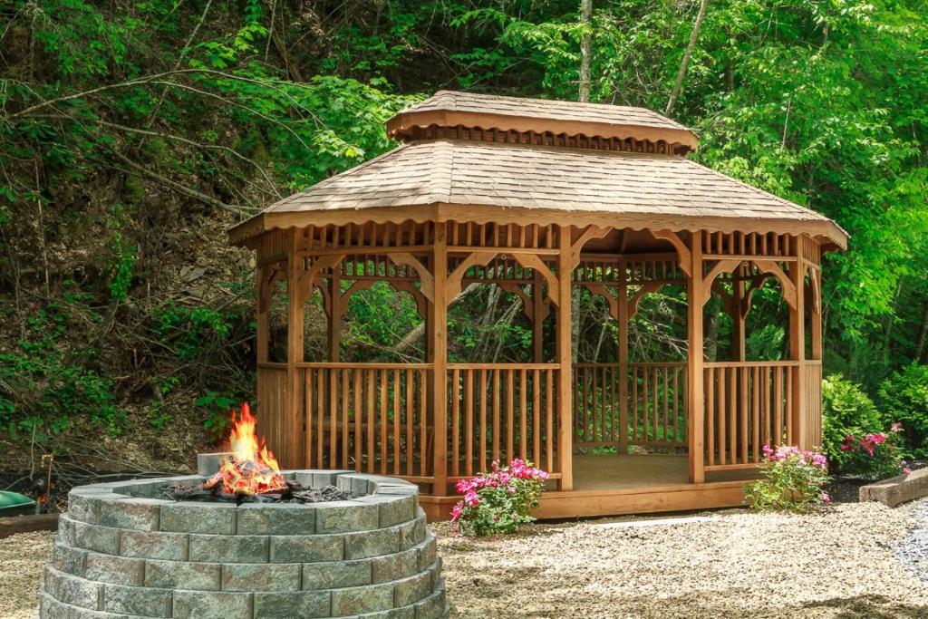 The shared gazebo and stone fire pit, flowers at its base · © Trail Head