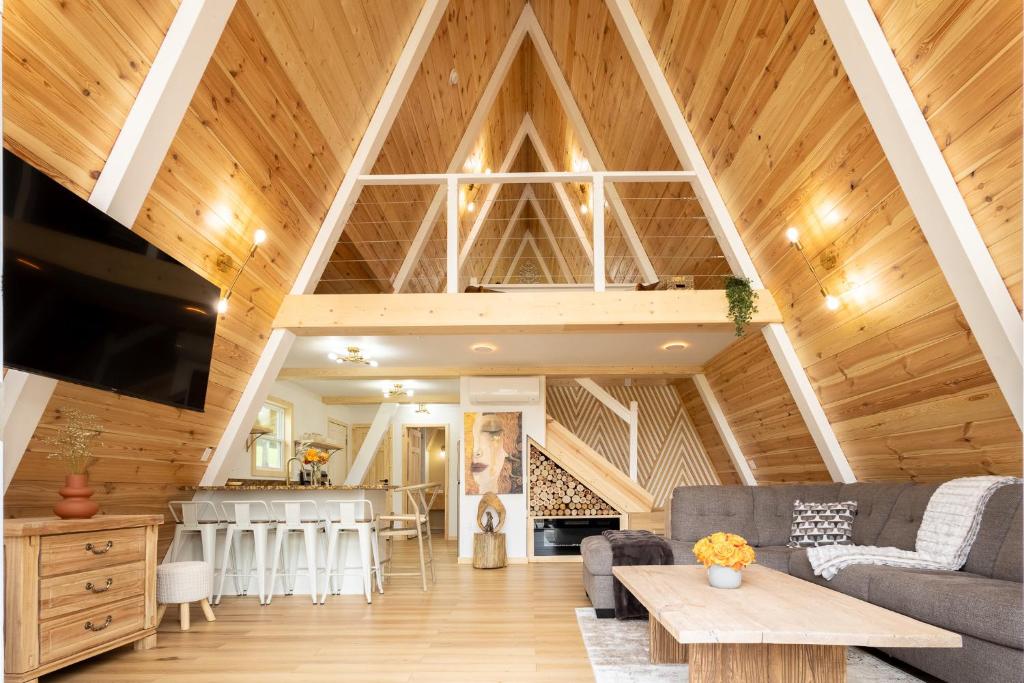 The great room under the peaked pine ceiling, kitchen and loft beyond · © Valhalla Cabins