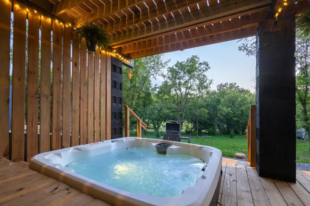 The private hot tub steaming on the covered deck at dusk · © Valhalla Cabins