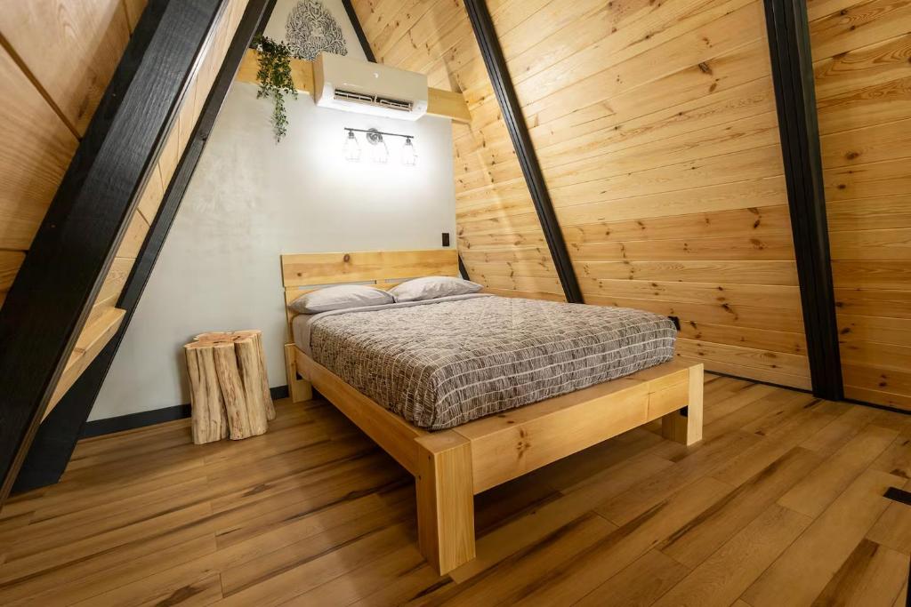 A queen bedroom set beneath the A-frame's sloping wall · © Valhalla Cabins