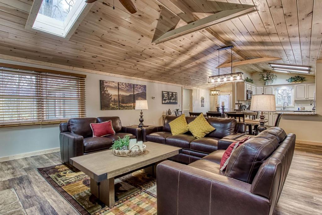 The open great room with leather sofas under a vaulted pine ceiling · © Whispering Winds