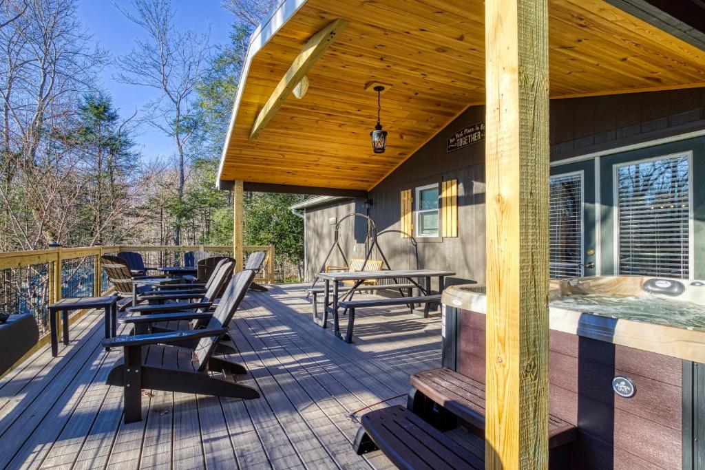 The covered deck with a hot tub, porch swing and Adirondack chairs · © Whispering Winds