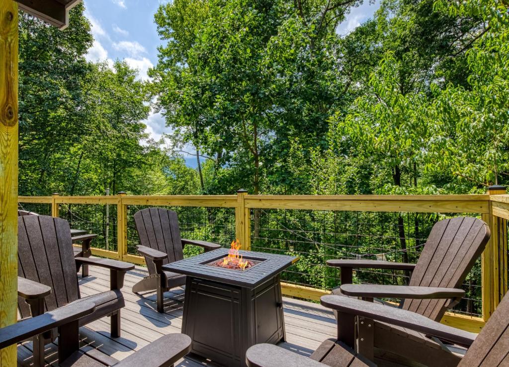 The open deck with a gas fire pit ringed by chairs and woods · © Whispering Winds