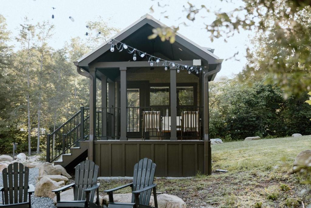 Adirondack chairs facing the string-lit covered porch · © Willow Cabin